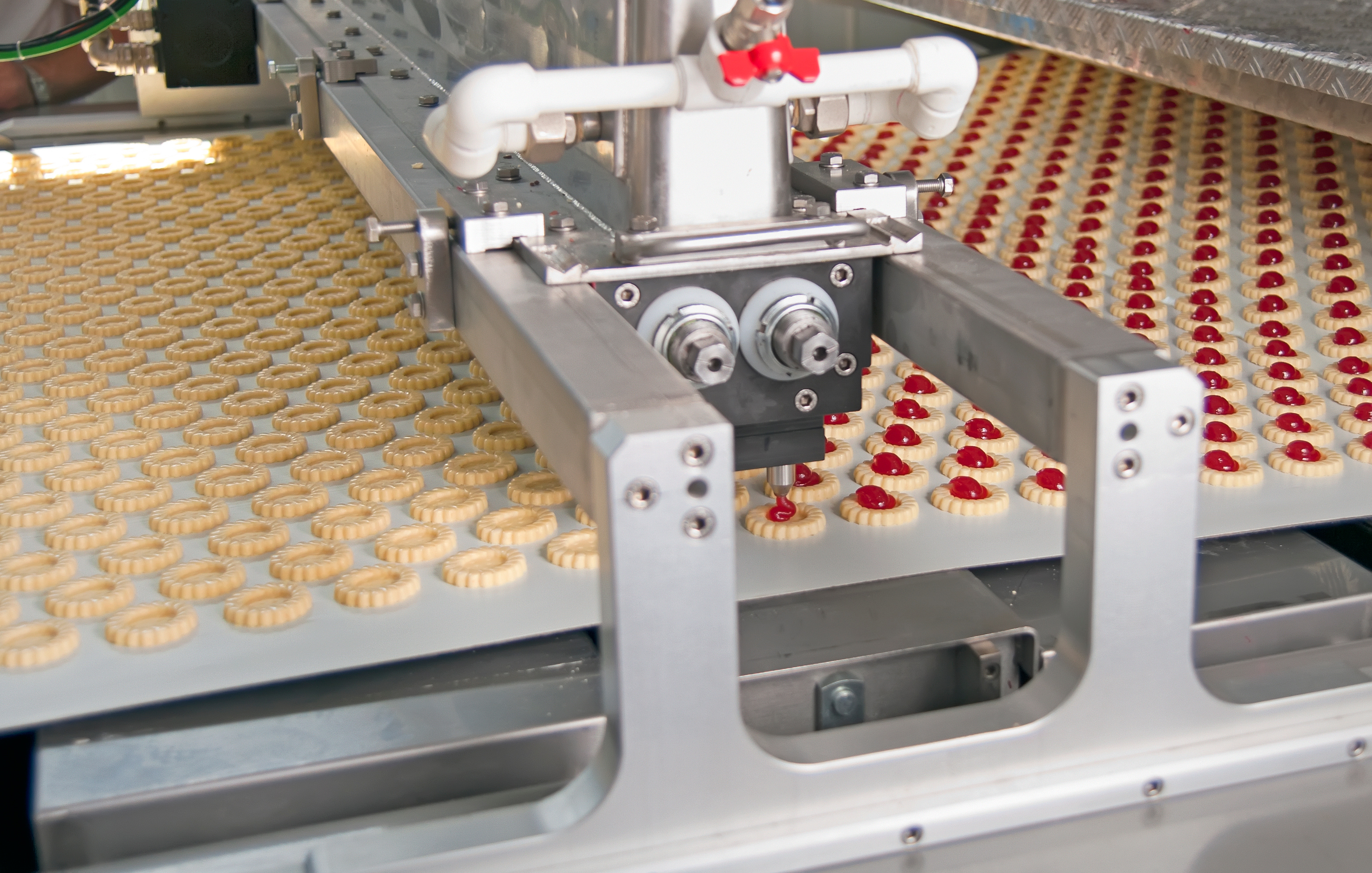 Industrial machinery filling cookies with jam