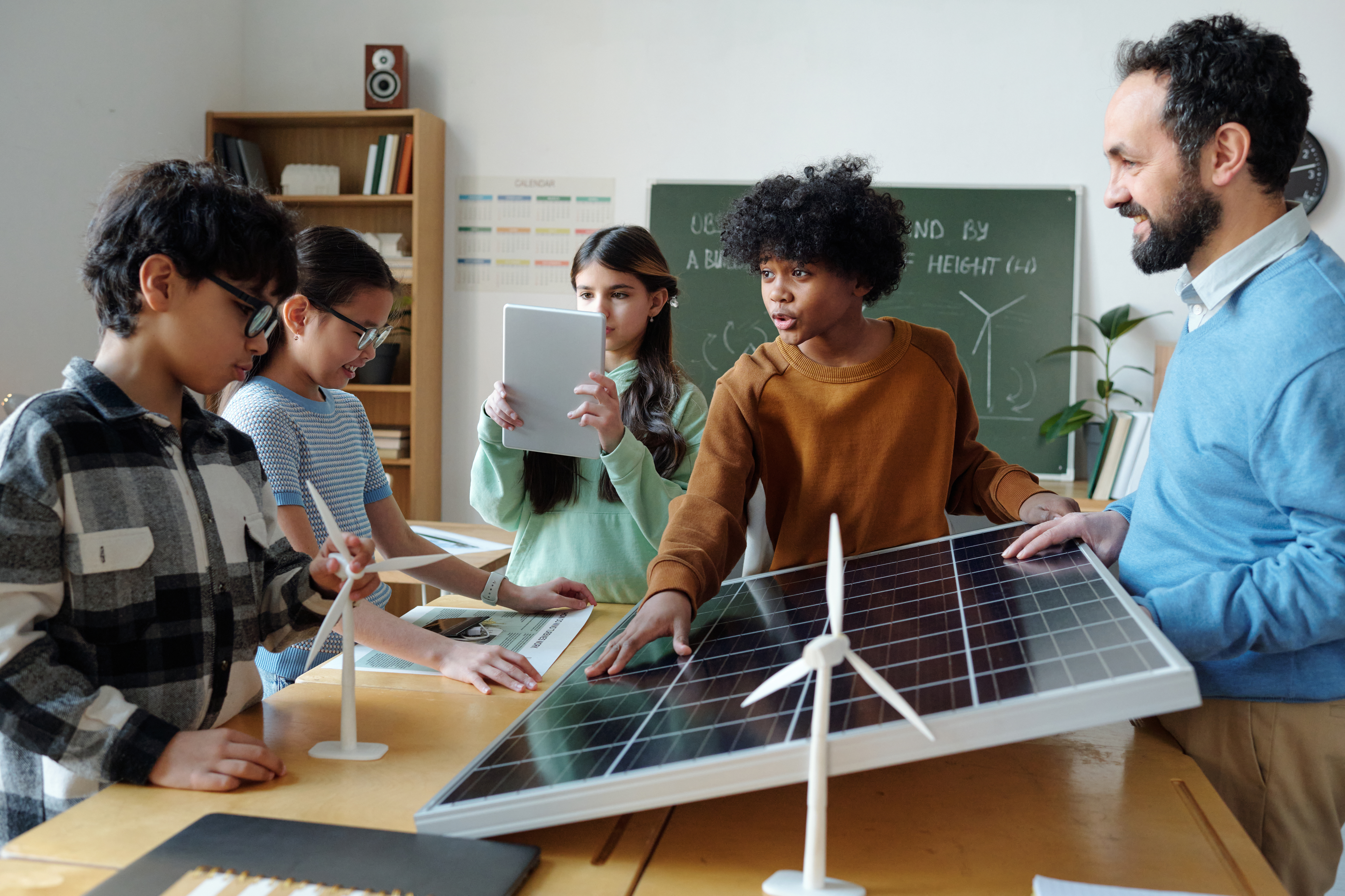 Teacher with students explaining renewable energy concepts including solar and wind