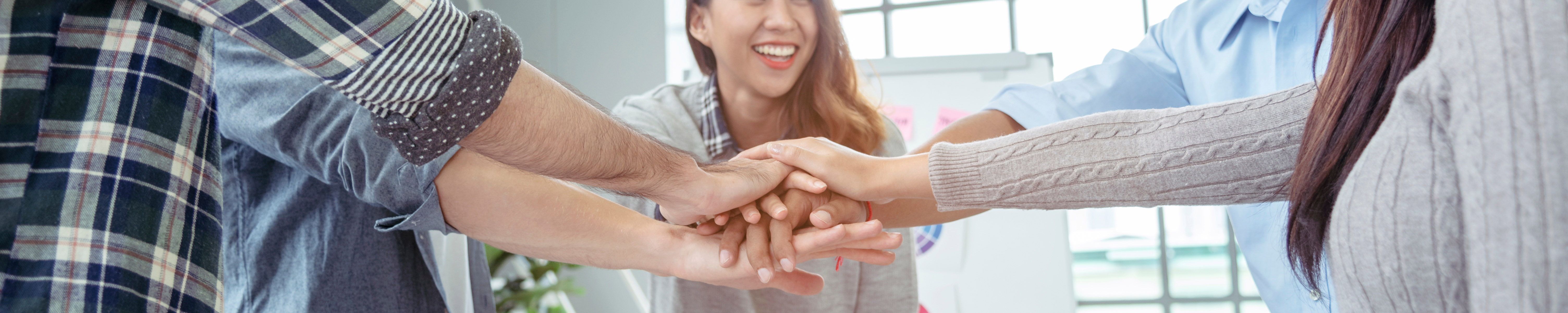 Smiling people with hands together in center