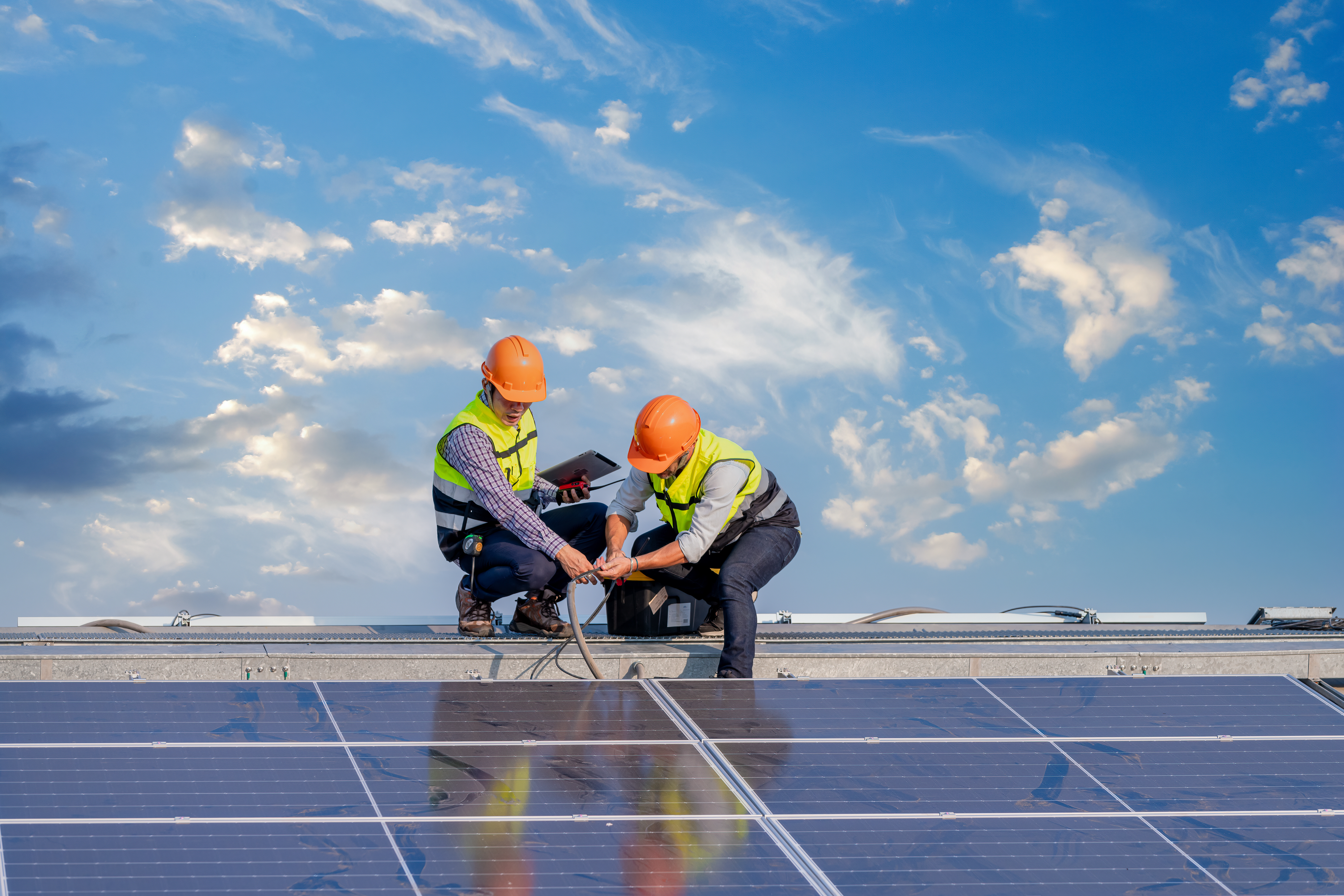 Two engineers looking at solar panels on a roof