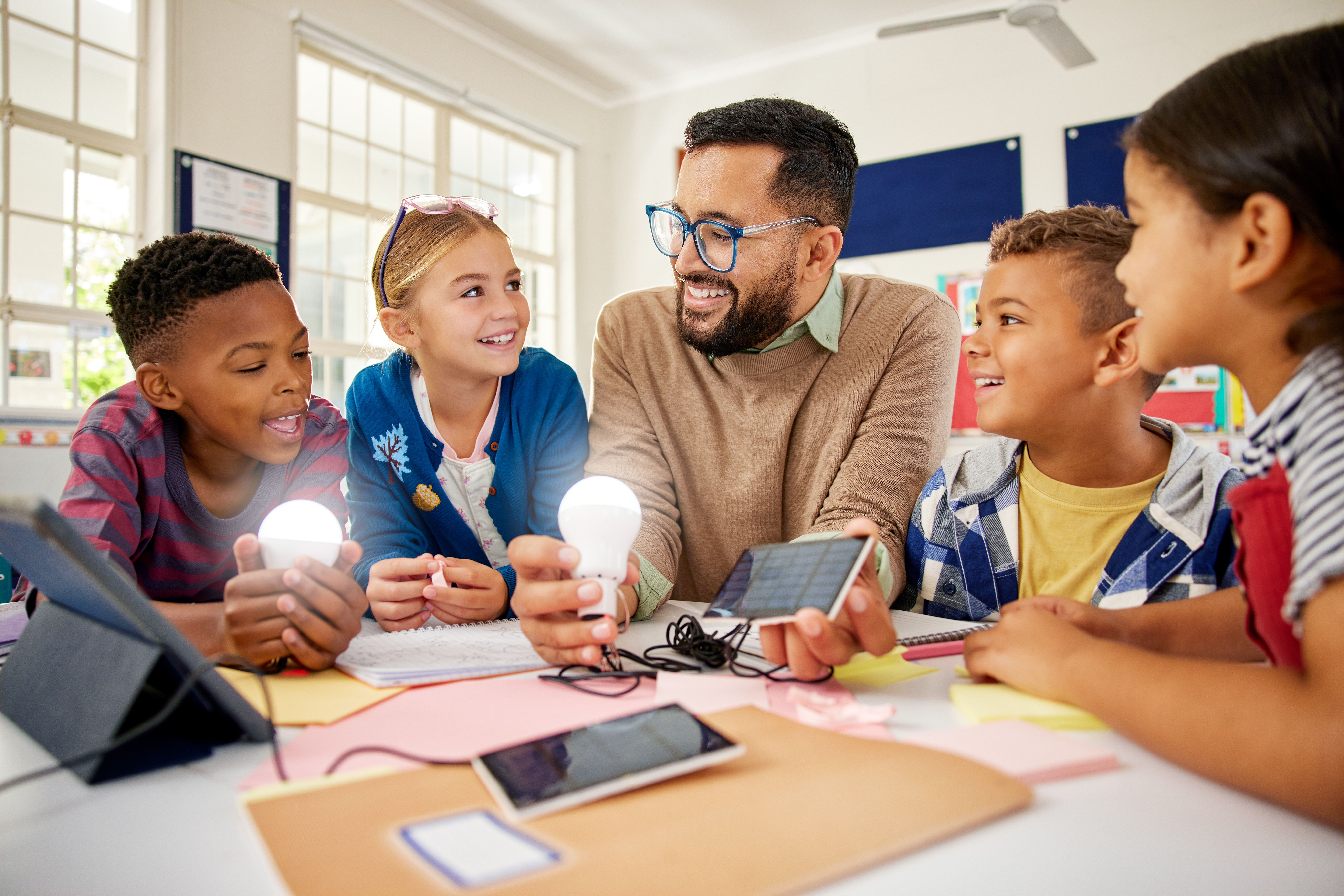 Students gathered around a teacher with light bulb and solar panel